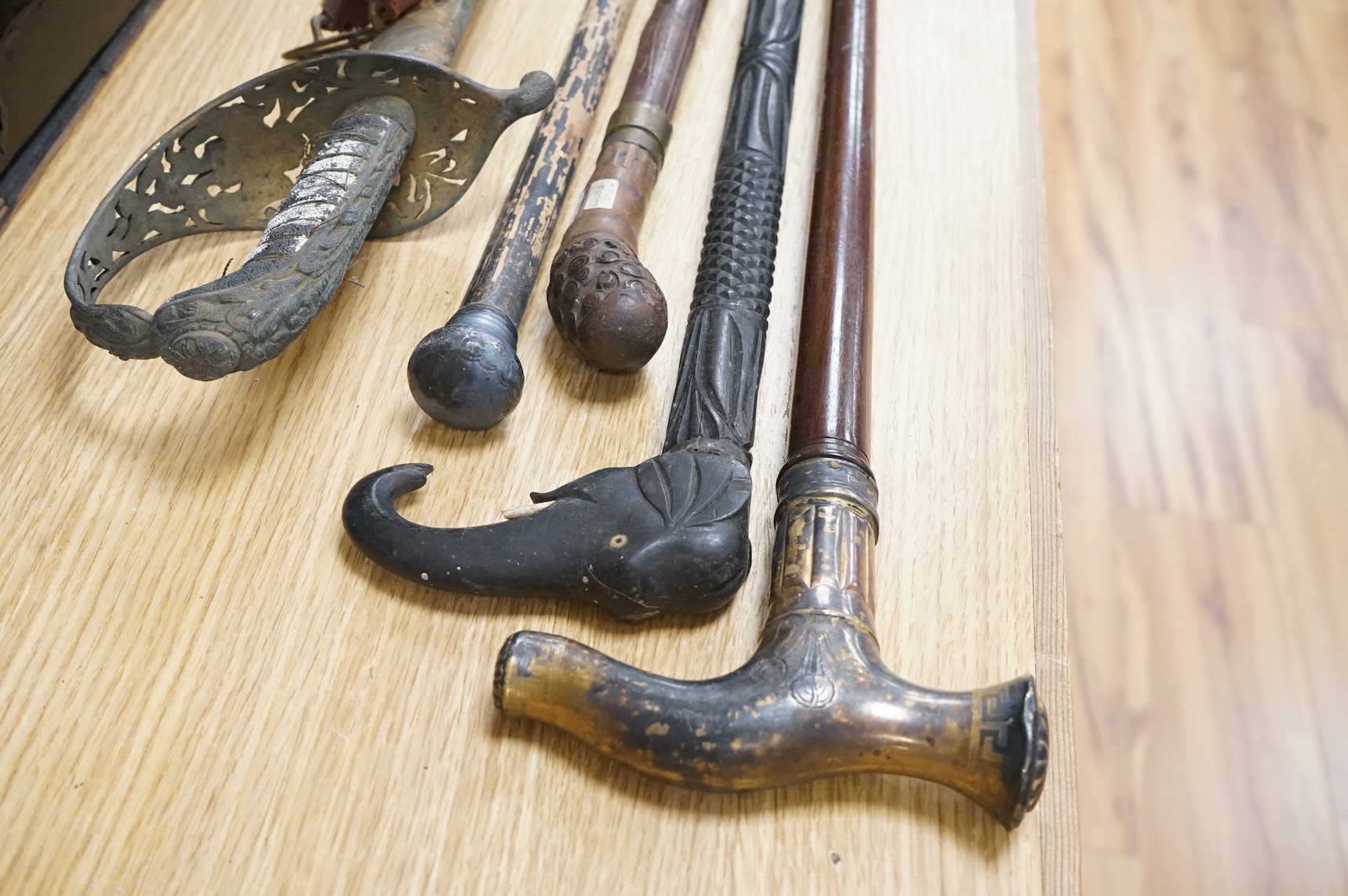 An officer’s sword, three walking sticks and an antique sword stick, longest walking stick 92cm long